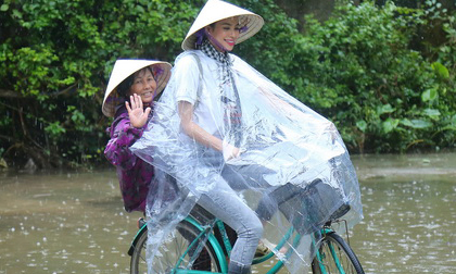 Phạm Hương chạy xe đạp chở cụ già giữa trời mưa dầm dề