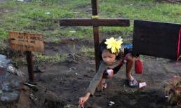 24h qua ảnh: Bé gái cắm kẹo mút lên mộ 4 người thân