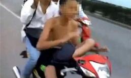 Thiếu niên cởi trần lái xe máy bằng một chân chở bạn
