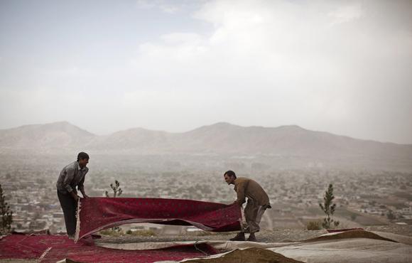 Hai người đàn ông đang thu dọn các tấm thảm sau một lễ an táng ông Burhanuddin Rabbani, cựu tổng thống Afghanistan ở Kabul.